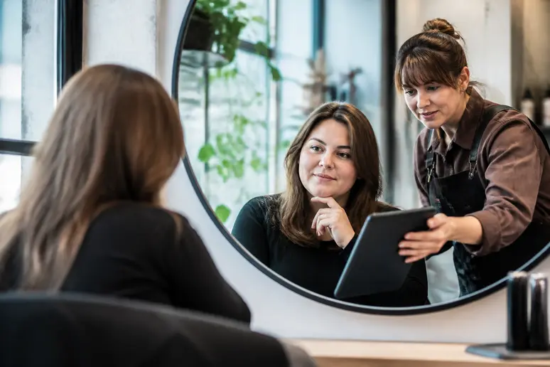 Une femme discute de son carré dégradé idéal avec une coiffeuse dans un salon de coiffure lumineux.