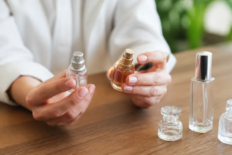 Petits flacons de parfum accessibles manipulés sur un comptoir en bois