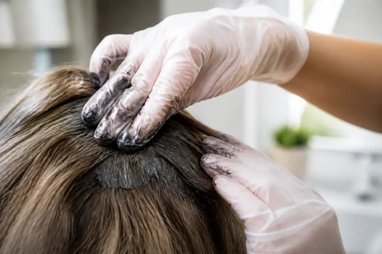 Mains gantées appliquant la mousse d'un shampoing colorant Novara Paris avis sur cheveux secs