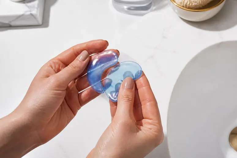 Application de patchs anti cernes en hydrogel frais sous les yeux devant un miroir.