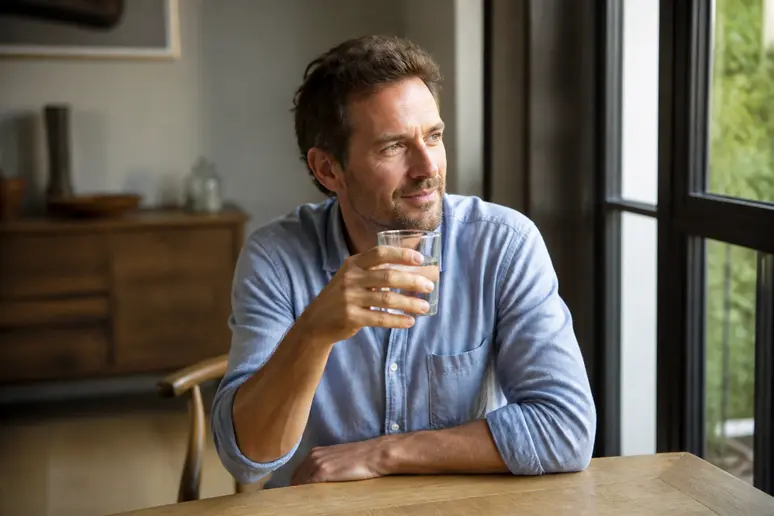 Personne tenant un verre d'eau pour maintenir une bonne hydratation et éviter les erreurs face au ventre gonflé
