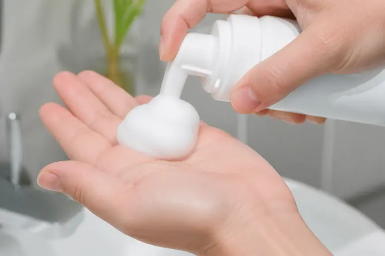 Flacon de minoxidil mousse retourné pour prélever un demi-bouchon de produit