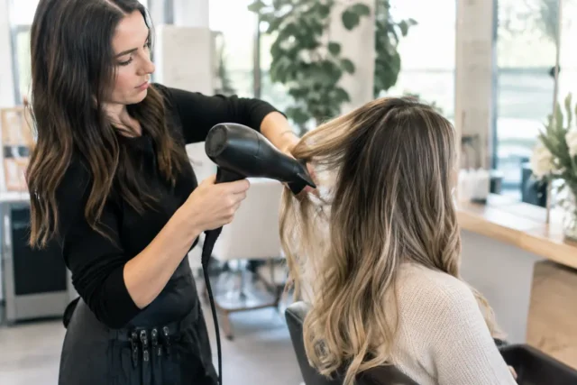 Un coiffeur réalise un airtouch balayage minutieux dans un salon lumineux