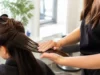 Coloration sans ammoniaque : vraie douceur ou éthanolamine ? Une coiffeuse applique délicatement un soin capillaire lors d'une séance de coloration sans ammoniaque en salon.