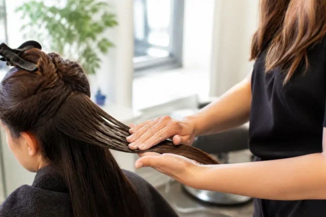 Coloration sans ammoniaque : vraie douceur ou éthanolamine ? Une coiffeuse applique délicatement un soin capillaire lors d'une séance de coloration sans ammoniaque en salon.