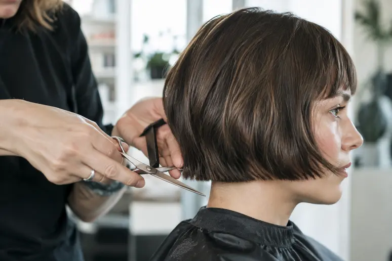 Coiffeur texturisant les pointes d'un french bob coupe pour alléger la masse
