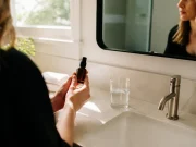 Jouvessence avis : effet tenseur réel ou traces blanches ? personne tenant un flacon de soin dans une salle de bains lumineuse pour son jouvessence avis