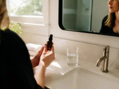 Jouvessence avis : effet tenseur réel ou traces blanches ? personne tenant un flacon de soin dans une salle de bains lumineuse pour son jouvessence avis