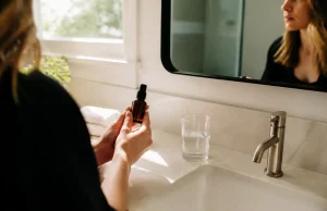 Jouvessence avis : effet tenseur réel ou traces blanches ? personne tenant un flacon de soin dans une salle de bains lumineuse pour son jouvessence avis