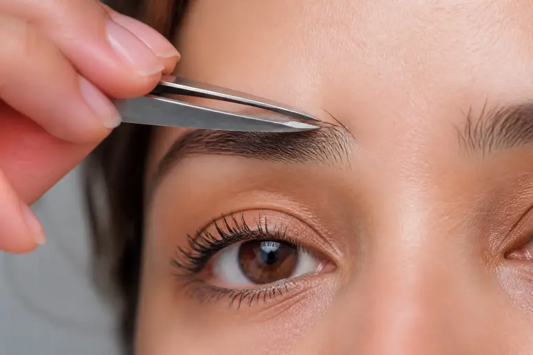 Utilisation d'une pince à épiler biseautée pour parfaire la ligne des sourcils d'un homme